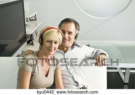 Stock Image - Couple listening to music with headphones and smiling. Fotosearch