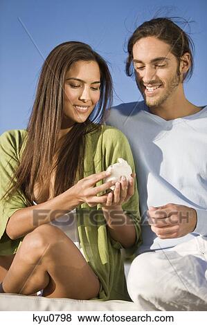 Stock Photo - Couple looking at a conch shell. Fotosearch