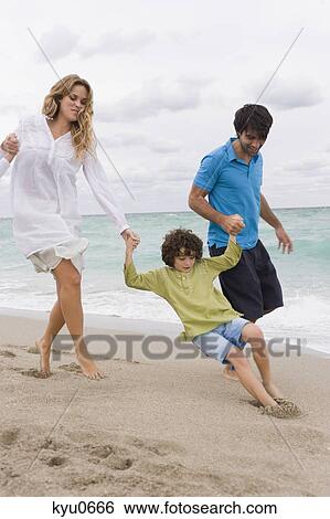 Stock Photograph - Couple playing with their son on the beach. Fotosearch