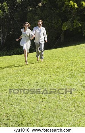 Stock Photograph - Couple running on grass. Fotosearch