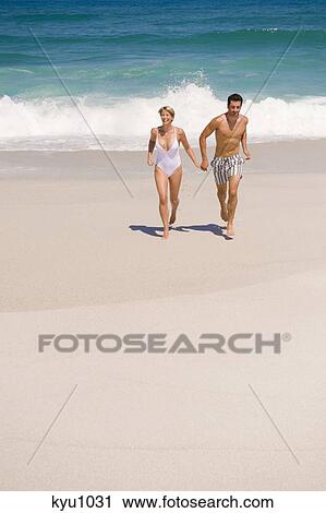 Stock Image - Couple running on the beach. Fotosearch