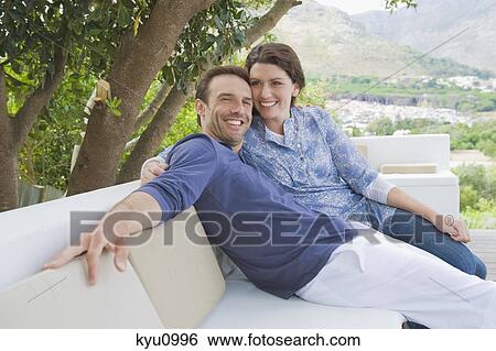 Couple sitting on a couch View Large Photo Image Stock Photograph - Couple sitting on a couch. Fotosearch