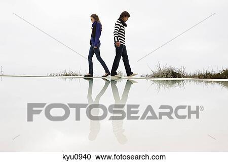 Couple walking on the ledge of a swimming pool View Large Photo Image Stock Image - Couple walking on the ledge of a swimming pool. Fotosearch