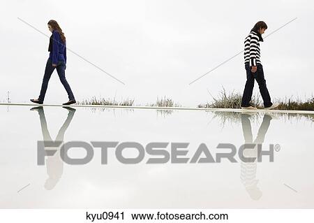 Couple walking on the ledge of a swimming pool View Large Photo Image Stock Image - Couple walking on the ledge of a swimming pool. Fotosearch