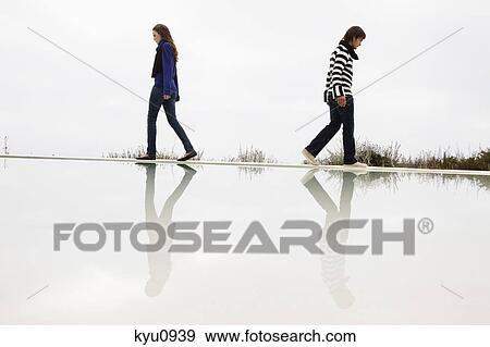 Stock Photo - Couple walking on the ledge of a swimming pool. Fotosearch