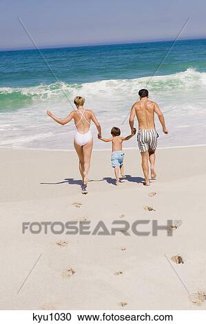 Stock Image - Family running on the beach. Fotosearch