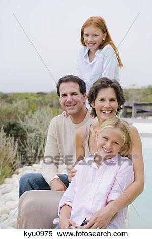 Stock Photography - Family sitting at the poolside. Fotosearch