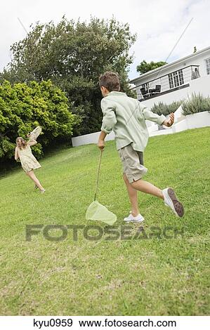 Stock Photo - Girl and a boy playing with butterfly nets in a garden. Fotosearch