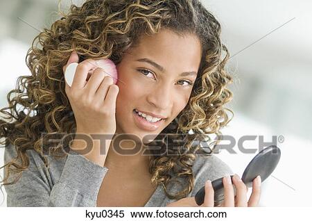 Girl applying make-up on her face View Large Photo Image Stock Photography - Girl applying make-up on her face. Fotosearch