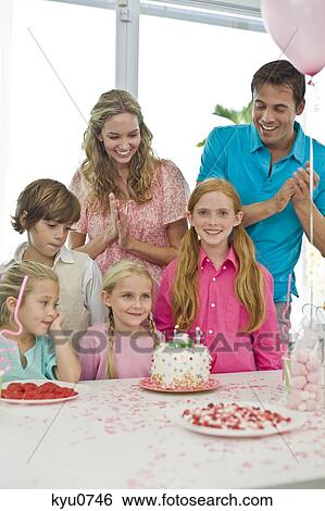 Stock Photograph - Girl celebrating her birthday with her parents and friends. Fotosearch