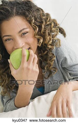 Girl eating an apple and smiling View Large Photo Image Stock Photo - Girl eating an apple and smiling. Fotosearch