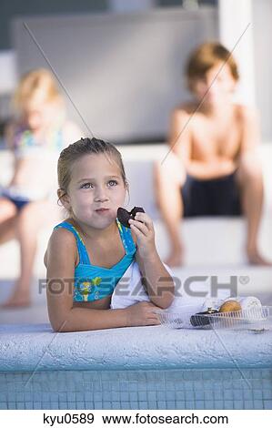 Girl eating chocolate donut at the poolside View Large Photo Image Stock Photo - Girl eating chocolate donut at the poolside. Fotosearch