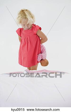 Girl holding a doll and looking serious View Large Photo Image Stock Photography - Girl holding a doll and looking serious. Fotosearch