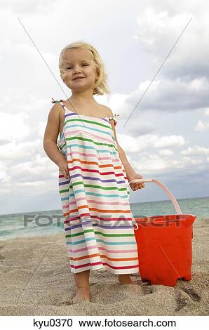 Girl holding a sand pail on the beach View Large Photo Image Stock Image - Girl holding a sand pail on the beach. Fotosearch
