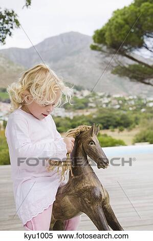 Girl playing with a rocking horse View Large Photo Image Stock Photography - Girl playing with a rocking horse. Fotosearch