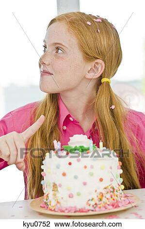 Stock Image - Girl pointing at a birthday cake. Fotosearch
