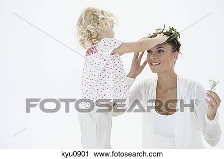 Stock Image - Girl putting a wreath on her mother's head. Fotosearch