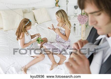 Groom adjusting his tie with two girls in the background View Large Photo Image Stock Photograph - Groom adjusting his tie with two girls in the background. Fotosearch
