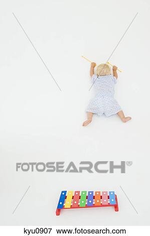 Stock Photo - High angle view of a baby boy fallen near a xylophone. Fotosearch