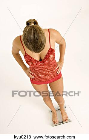 High angle view of a young woman standing on a bathroom scale View Large Photo Image Stock Photo - High angle view of a young woman standing on a bathroom scale. Fotosearch