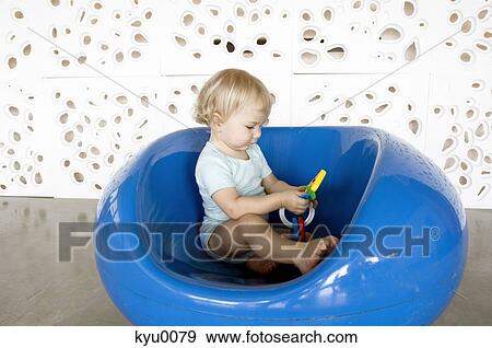 Stock Photo - Little boy playing, sitting in a blue chair. Fotosearch