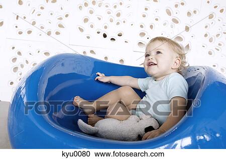 Stock Image - Little boy sitting in a blue chair. Fotosearch