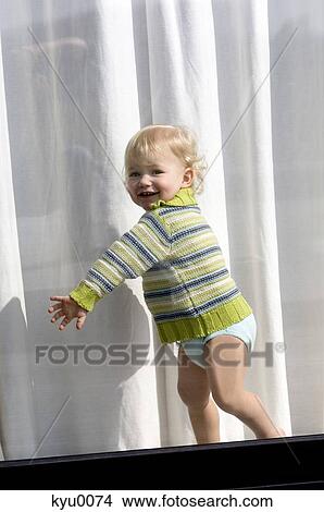 Picture - Little boy standing behind window. Fotosearch