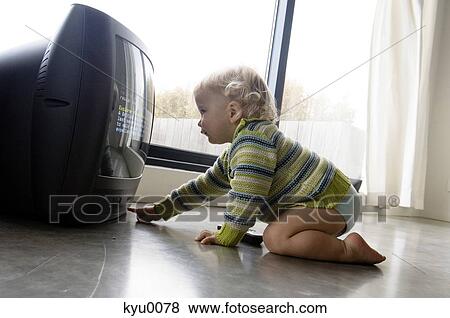 Stock Photo - Little boy turning on TV. Fotosearch