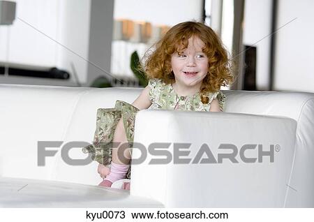 Little girl sitting on a sofa View Large Photo Image Stock Image - Little girl sitting on a sofa. Fotosearch