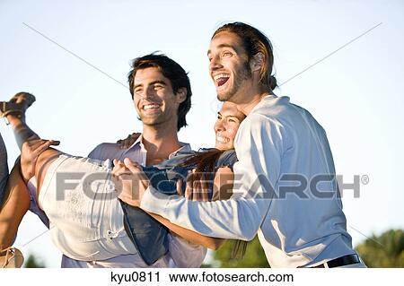 Man carrying a woman with his friend standing beside him View Large Photo Image Stock Image - Man carrying a woman with his friend standing beside him. Fotosearch