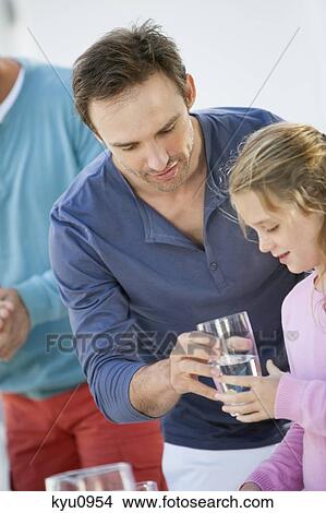 Picture - Man giving a glass of water to her daughter. Fotosearch