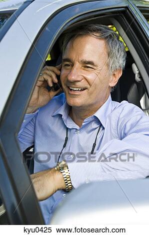 Man in a car and talking on a mobile phone View Large Photo Image Stock Photography - Man in a car and talking on a mobile phone. Fotosearch