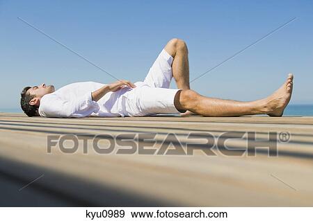 Man lying on a boardwalk on the beach View Large Photo Image Stock Photo - Man lying on a boardwalk on the beach. Fotosearch