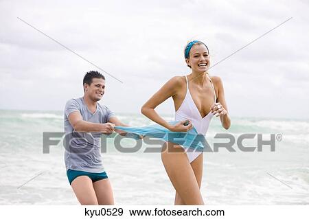 Man pulling sarong of a woman on the beach View Large Photo Image Stock Photo - Man pulling sarong of a woman on the beach. Fotosearch