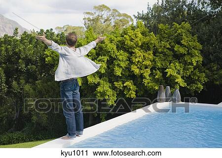 Man standing at the poolside with his arms outstretched View Large Photo Image Stock Image - Man standing at the poolside with his arms outstretched. Fotosearch