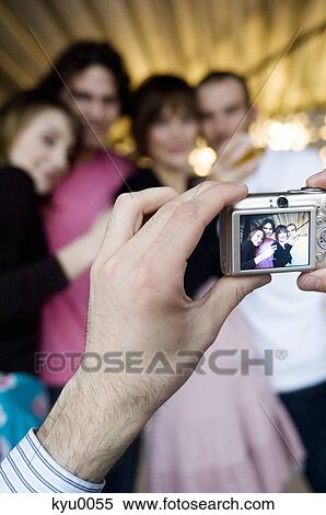 Stock Photography - Man taking picture of 2 smiling couples. Fotosearch
