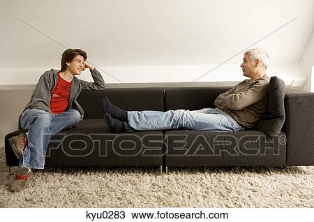 Mature man and his son sitting on a couch and looking at each other View Large Photo Image Stock Image - Mature man and his son sitting on a couch and looking at each other. Fotosearch