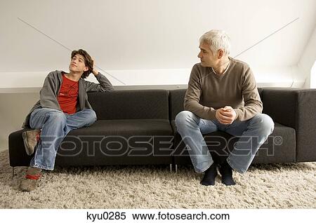 Mature man and his son sitting on a couch View Large Photo Image Stock Photography - Mature man and his son sitting on a couch. Fotosearch