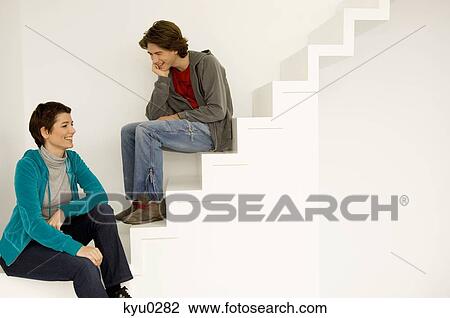 Stock Image - Mid adult woman and her son sitting on a staircase. Fotosearch