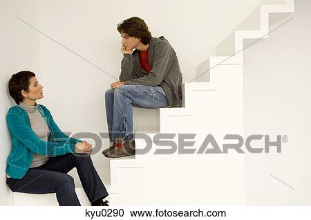 Stock Image - Mid adult woman and her son sitting on a staircase. Fotosearch