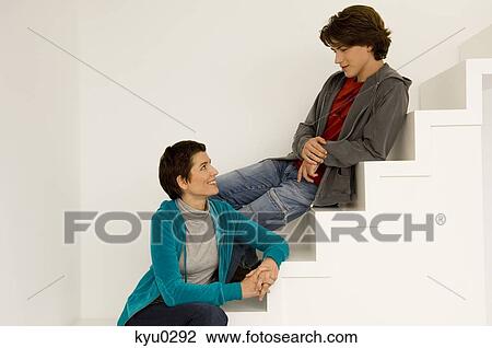 Stock Image - Mid adult woman and her son sitting on a staircase. Fotosearch