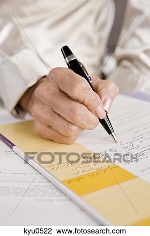Stock Image - Mid section view of a woman filling out an application form. Fotosearch