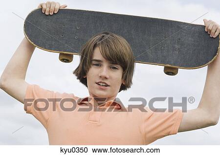Portrait of a boy holding a skateboard over his head View Large Photo Image Stock Image - Portrait of a boy holding a skateboard over his head. Fotosearch