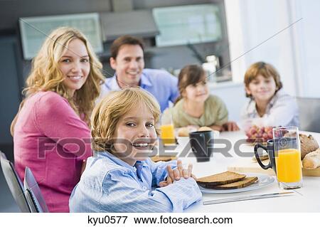 Stock Photo - Portrait of a family having breakfast and smiling. Fotosearch