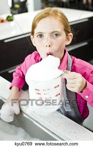 Stock Photo - Portrait of a girl blowing soap suds in a measuring jug. Fotosearch