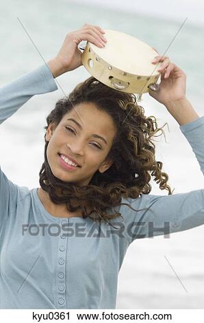 Portrait of a girl holding a tambourine over her head View Large Photo Image Stock Image - Portrait of a girl holding a tambourine over her head. Fotosearch