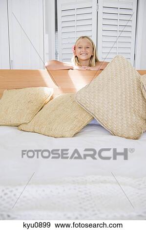 Portrait of a girl leaning on a bed and smiling View Large Photo Image Stock Photo - Portrait of a girl leaning on a bed and smiling. Fotosearch