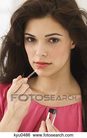 Portrait of a woman applying lip liner on her lips View Large Photo Image Stock Photograph - Portrait of a woman applying lip liner on her lips. Fotosearch