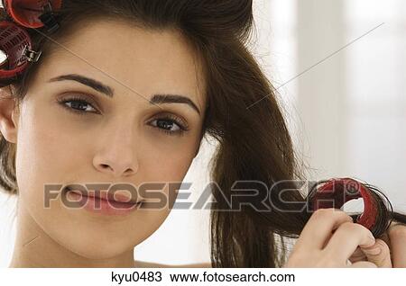 Stock Image - Portrait of a woman removing hair curlers. Fotosearch