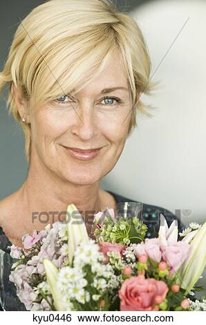 Stock Photograph - Portrait of a woman smiling with a bouquet of flowers. Fotosearch
